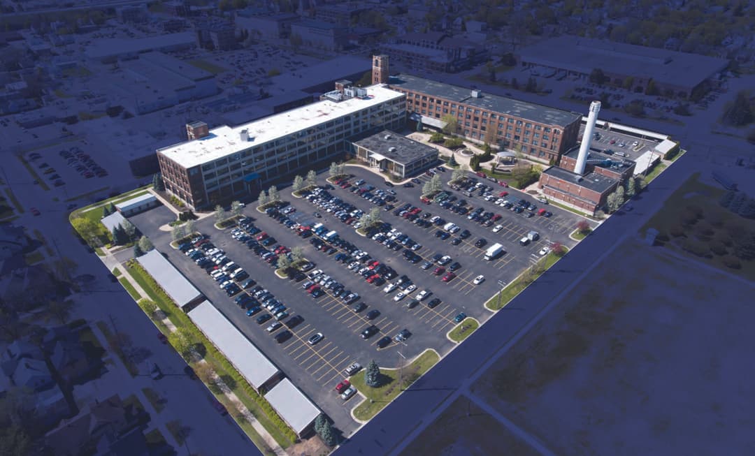 Aerial view of American Seating Park in Grand Rapids, Michigan: multi-story brick industrial buildings around a large parking lot
