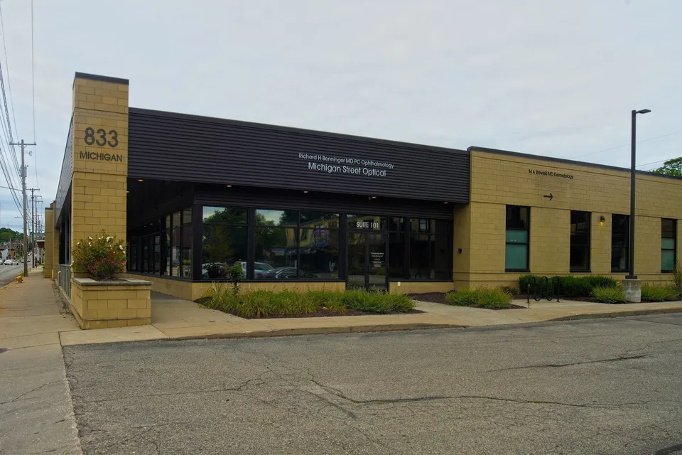 Street view of 833 Michigan Street NE, a single-story tan block building with dark metal canopy and 833 signage