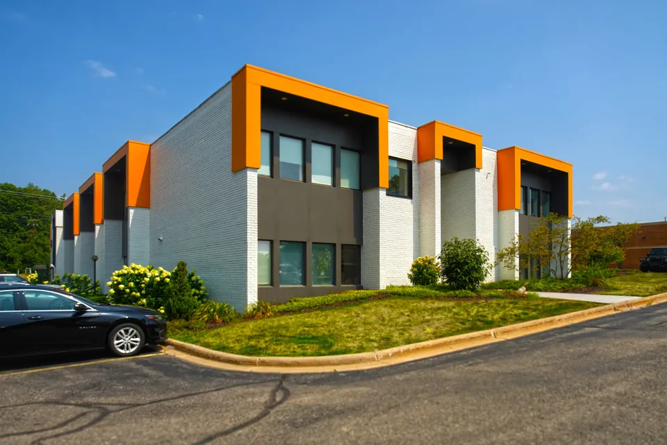 Corner view of 4500 Cascade Road SE, a two-story white office building with orange window surrounds